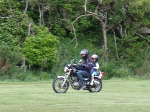 Charli riding on the back of her headmaster's motorbike