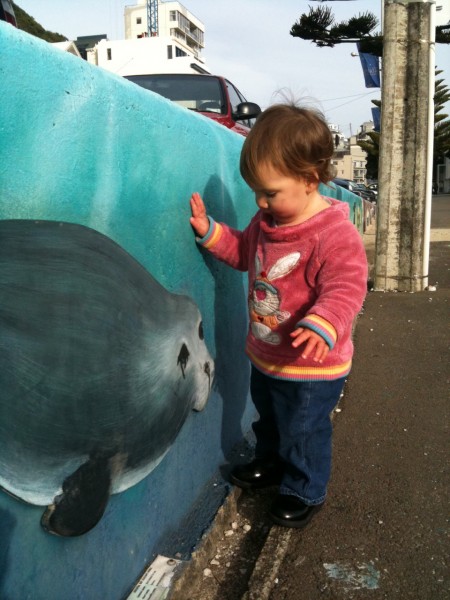 Alice looking at the NZ Fur Seal painting on Oriental Parade