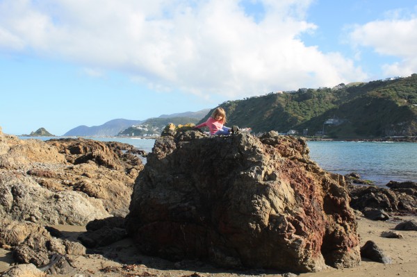 Sophie on a rock at Princess Bay - with Island Bay in the distance