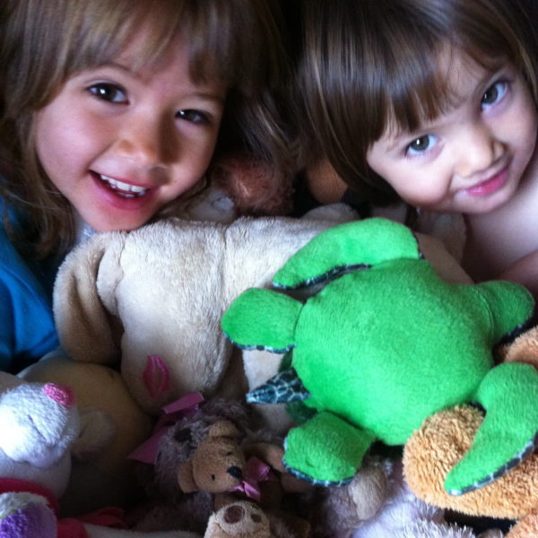 Sophie & Alice hiding in a pile of cuddly toys