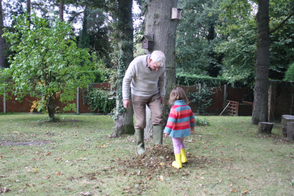 Granddad and Alice at home in the garden kicking up the Autumn leaves