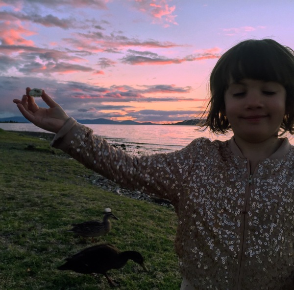Alice feeding the ducks, on the shore of Lake Taupo, at sunset.