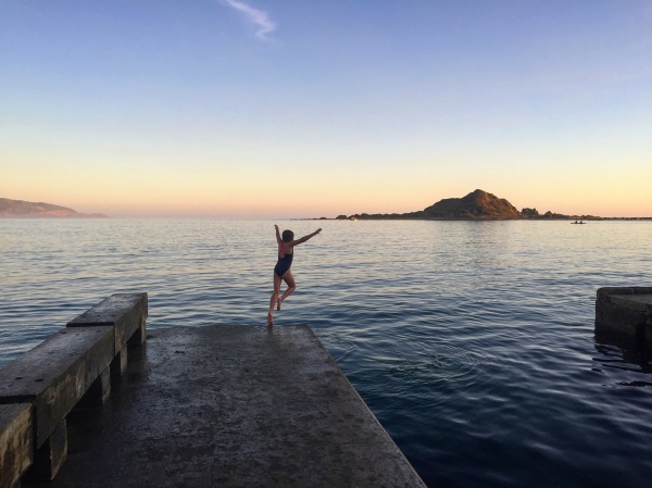 Jumping into the sea at sunset in Island Bay.