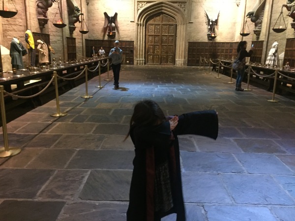 Alice, wearing her cloak, and 'dabbing' in 'The Great Hall'.