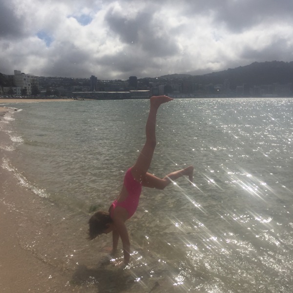 Sophie hand-standing at Oriental Parade beach on a sunny spring day.